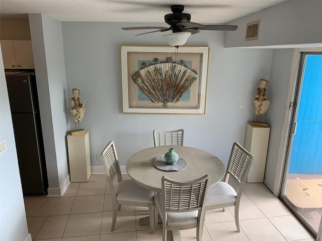 tiled dining area featuring a textured ceiling and ceiling fan