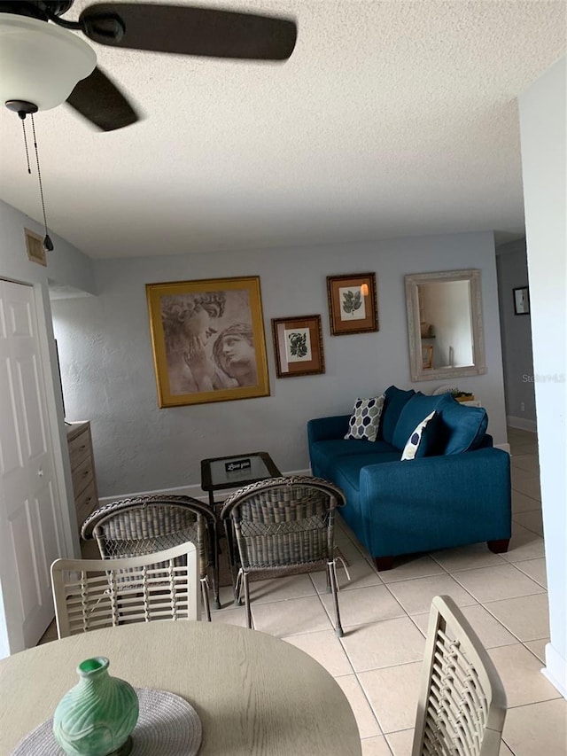 tiled dining room with a textured ceiling and ceiling fan