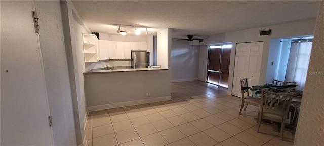 kitchen with sink, light tile patterned flooring, a textured ceiling, white cabinets, and stainless steel refrigerator