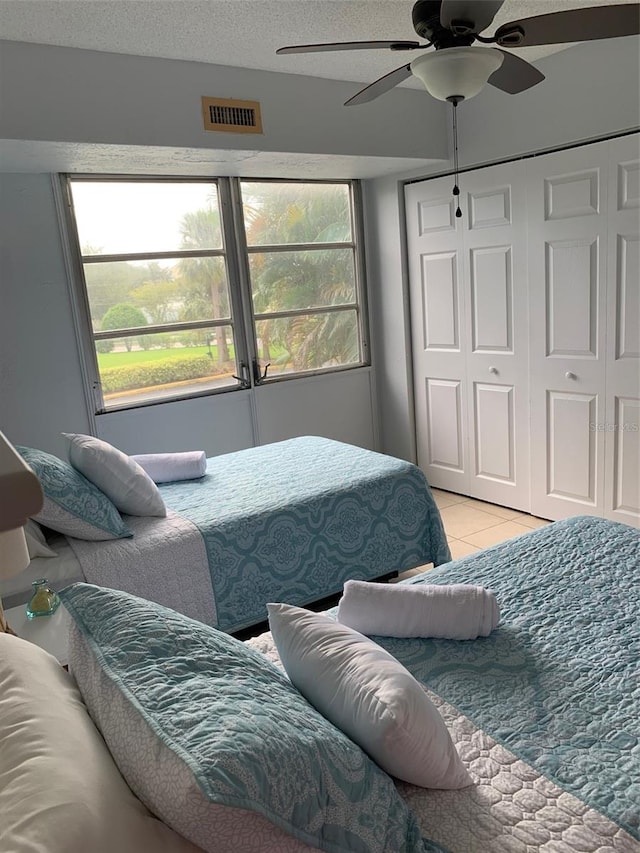 tiled bedroom with a textured ceiling, multiple windows, and ceiling fan