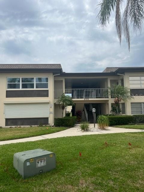 view of front of property featuring a balcony and a front yard