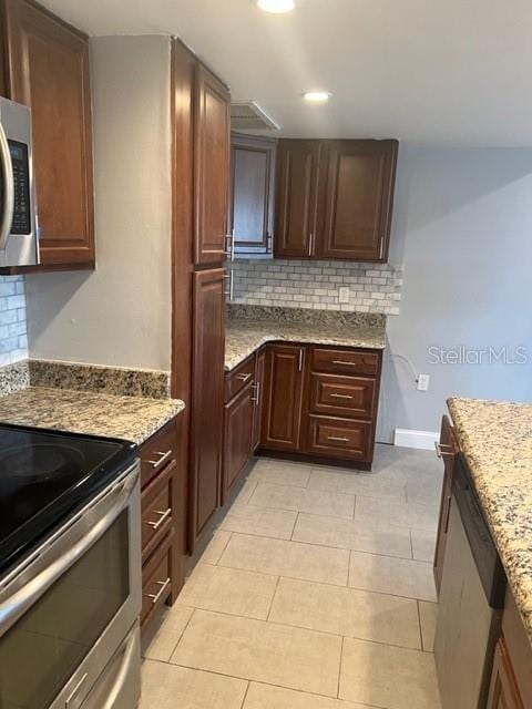 kitchen featuring backsplash, stainless steel appliances, light tile flooring, and light stone countertops