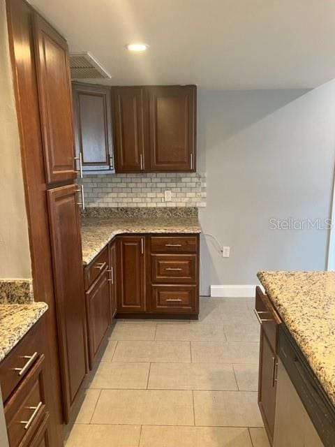 kitchen featuring light tile floors, light stone countertops, backsplash, and dark brown cabinetry