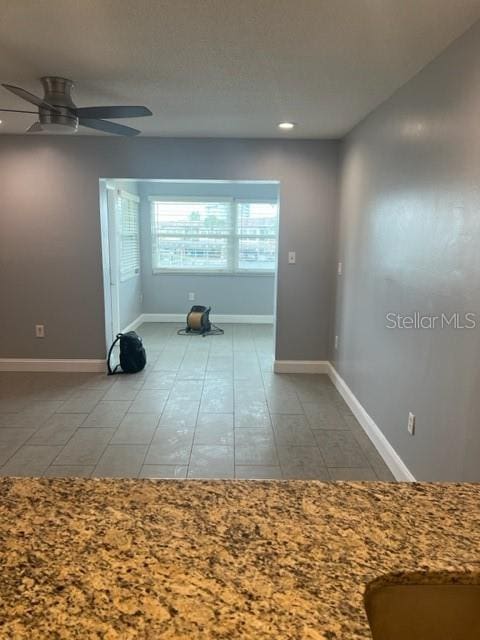 tiled spare room with ceiling fan