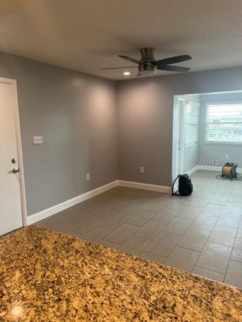 tiled empty room featuring ceiling fan