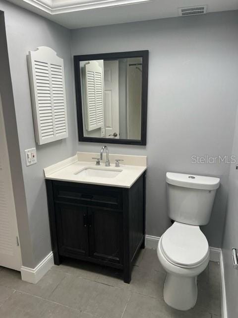 bathroom with toilet, tile flooring, and vanity