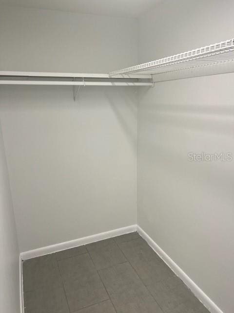 walk in closet with dark tile flooring