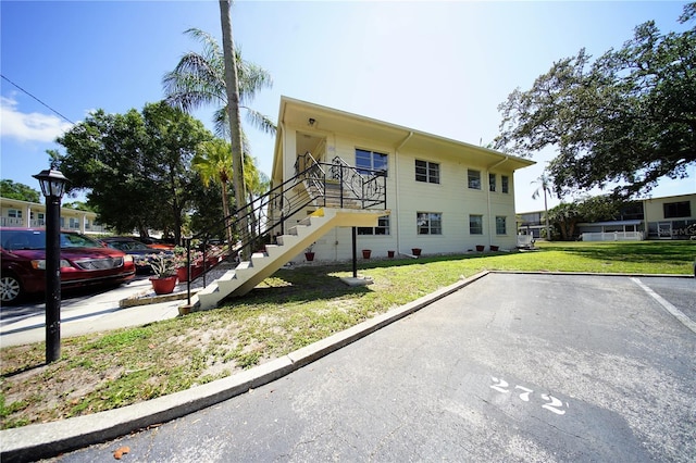 view of front of house with uncovered parking, stairway, and a front yard