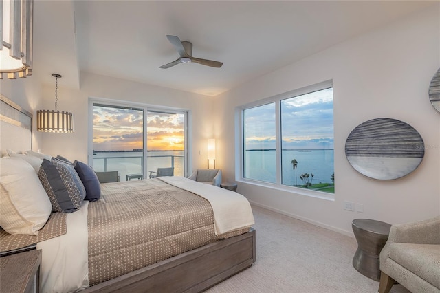 carpeted bedroom featuring a water view and ceiling fan