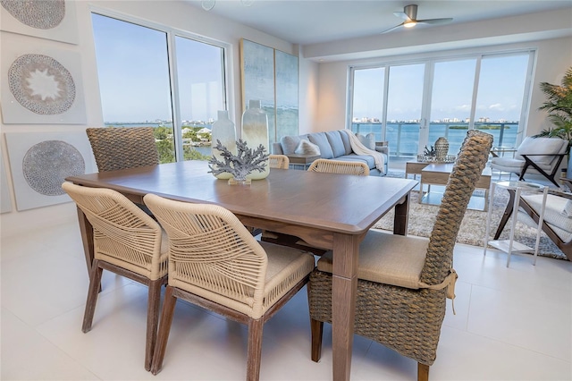 tiled dining space featuring ceiling fan and a water view