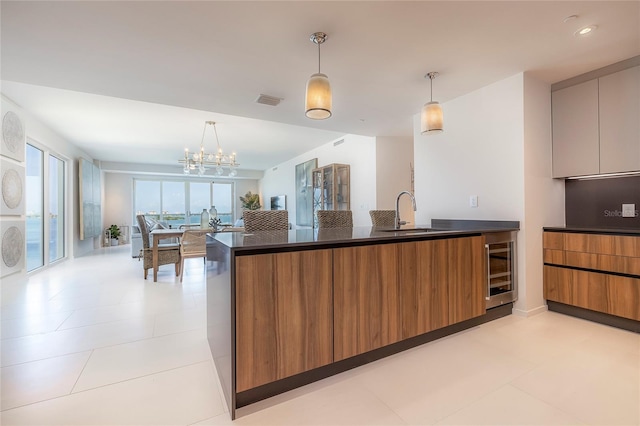 kitchen with light tile floors, beverage cooler, sink, a chandelier, and pendant lighting