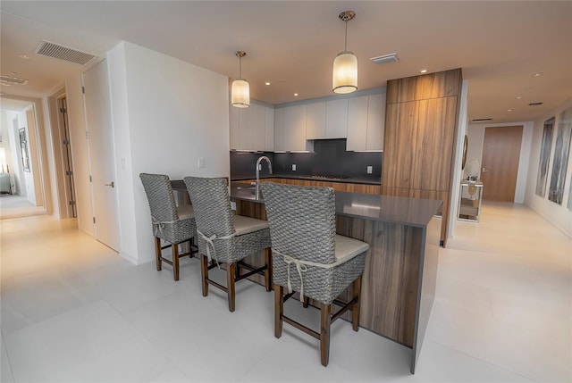 kitchen with backsplash, a breakfast bar, hanging light fixtures, and light tile floors