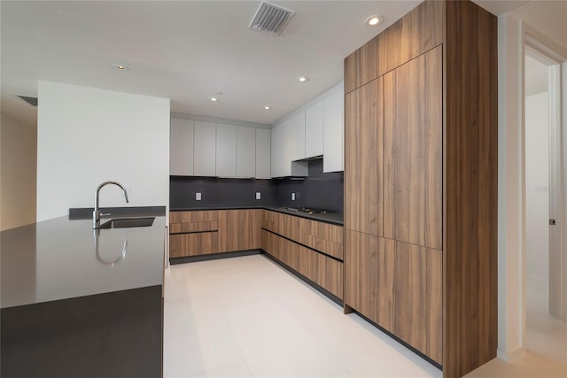 kitchen featuring gas cooktop, tasteful backsplash, white cabinets, sink, and light tile flooring