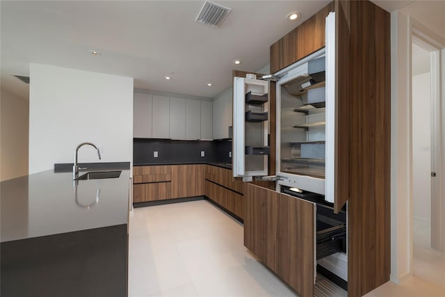 kitchen featuring white cabinets, backsplash, sink, and light tile flooring