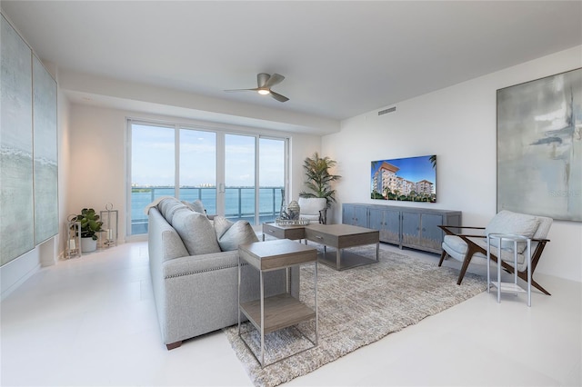 tiled living room featuring ceiling fan and a water view