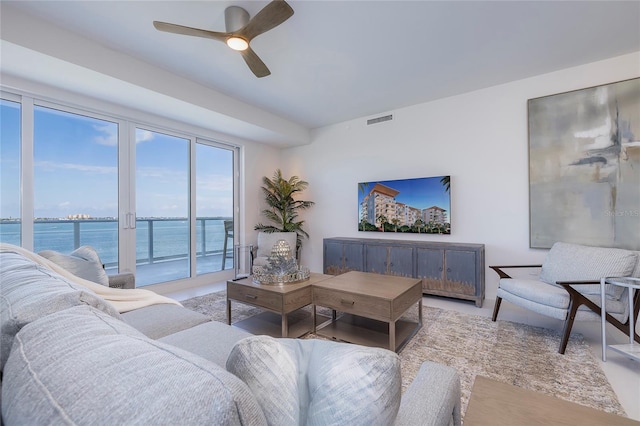 living room featuring ceiling fan and a water view