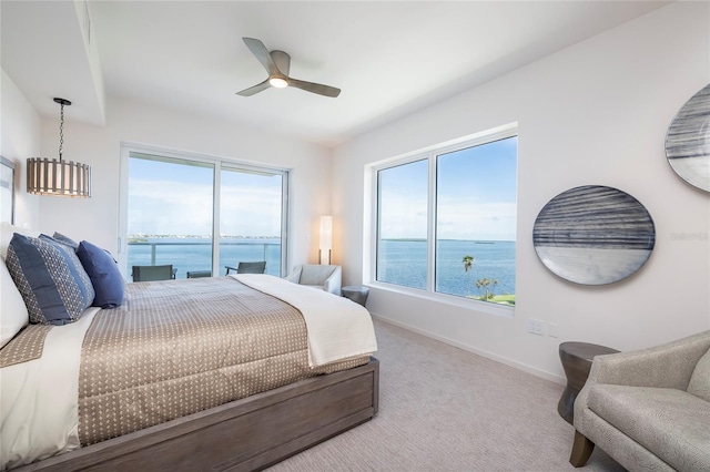 carpeted bedroom featuring a water view, access to outside, and ceiling fan with notable chandelier