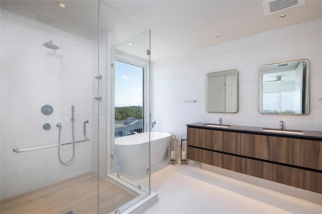 bathroom featuring tile flooring, shower with separate bathtub, large vanity, and tile walls