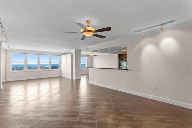 spare room featuring ceiling fan, a water view, dark tile patterned floors, and a textured ceiling