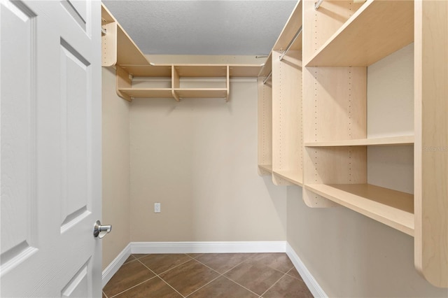 walk in closet with dark tile patterned flooring