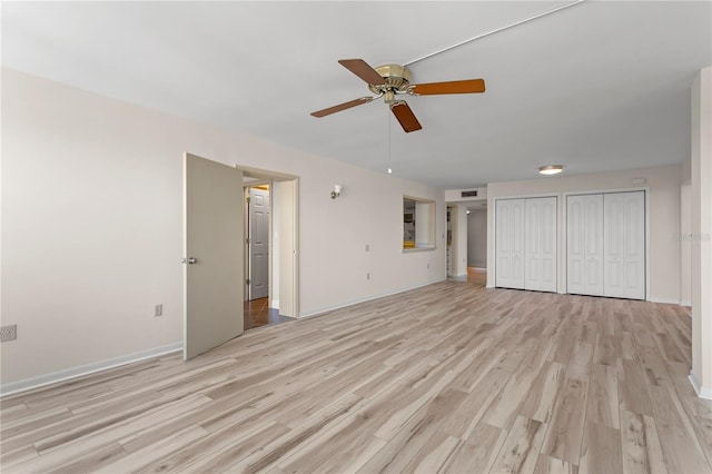 unfurnished bedroom with ceiling fan, light hardwood / wood-style floors, and two closets