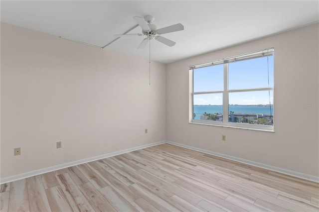 unfurnished room with a water view, light hardwood / wood-style flooring, and ceiling fan