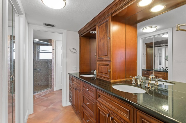 bathroom featuring tile patterned floors, vanity, an enclosed shower, and a textured ceiling