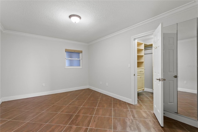 unfurnished bedroom with a walk in closet, a closet, a textured ceiling, and ornamental molding