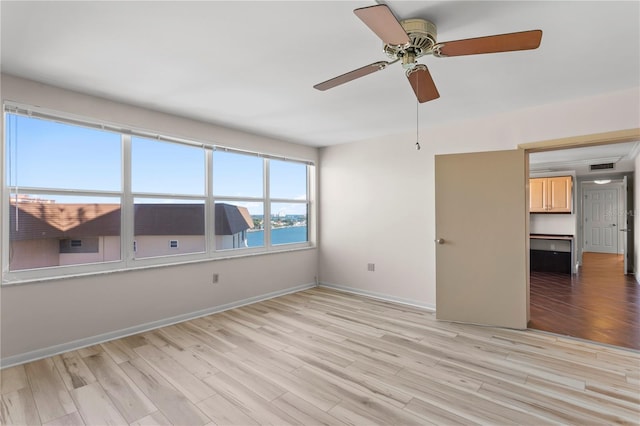 empty room featuring a water view, ceiling fan, and light hardwood / wood-style floors