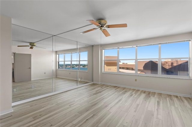 empty room with ceiling fan and light hardwood / wood-style floors