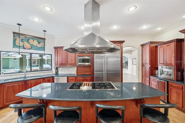 kitchen featuring built in appliances, a kitchen breakfast bar, island range hood, and sink