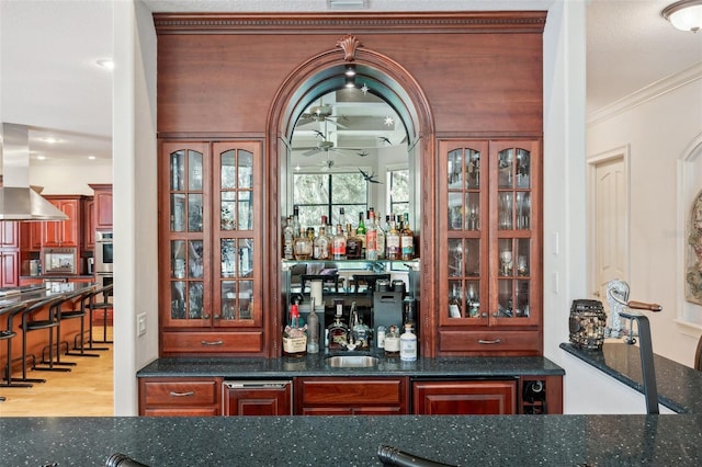 bar featuring ceiling fan, crown molding, exhaust hood, dark stone countertops, and light hardwood / wood-style floors