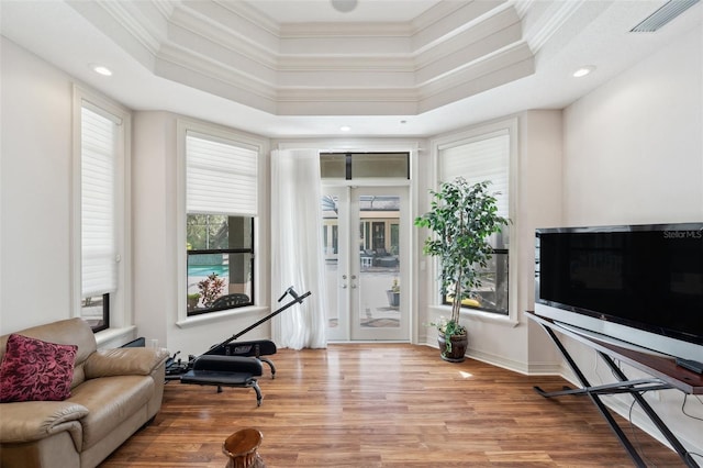 interior space featuring a tray ceiling, crown molding, and light wood-type flooring