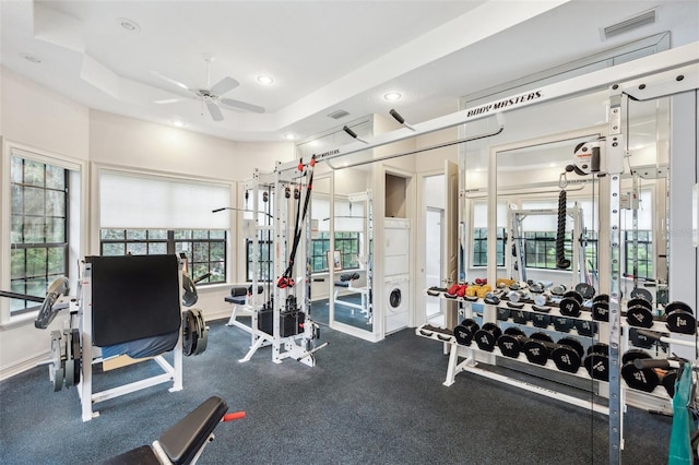 workout area featuring a raised ceiling and ceiling fan