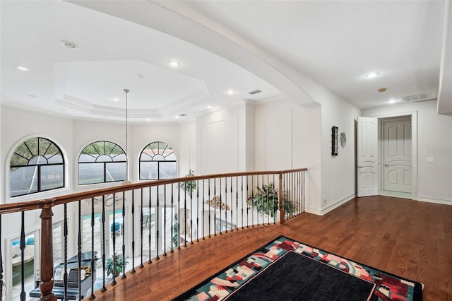 corridor with hardwood / wood-style flooring and a tray ceiling