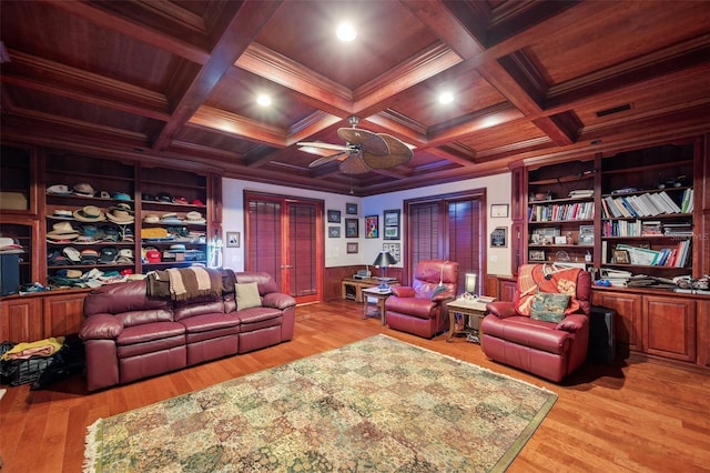 cinema room featuring coffered ceiling, ceiling fan, crown molding, light hardwood / wood-style flooring, and beamed ceiling