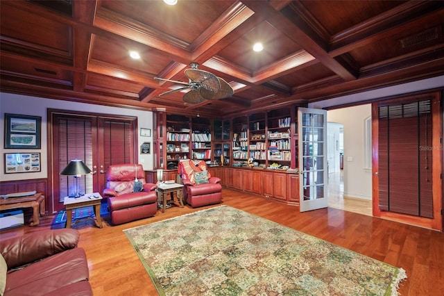 living room featuring coffered ceiling, ceiling fan, light wood-type flooring, ornamental molding, and beam ceiling