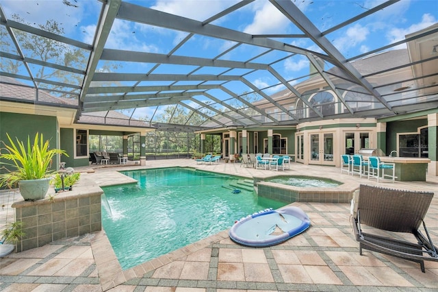 view of pool featuring glass enclosure, a patio area, a bar, and an in ground hot tub