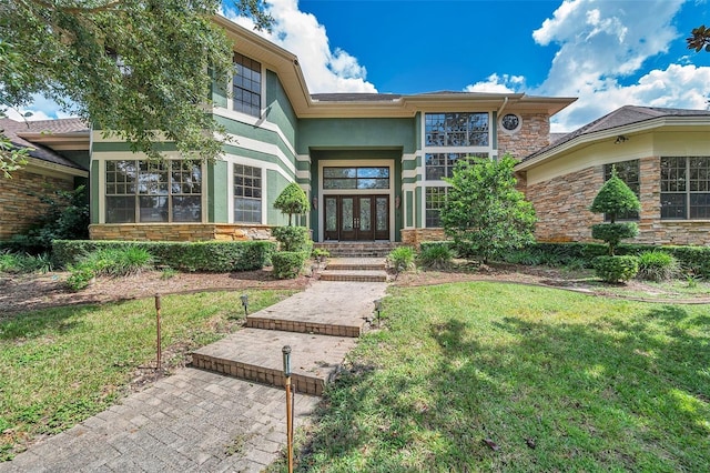 view of exterior entry with a lawn and french doors