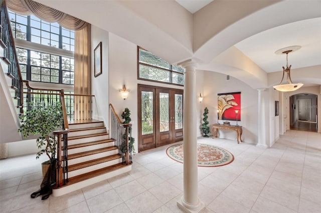 tiled foyer featuring ornate columns and a towering ceiling