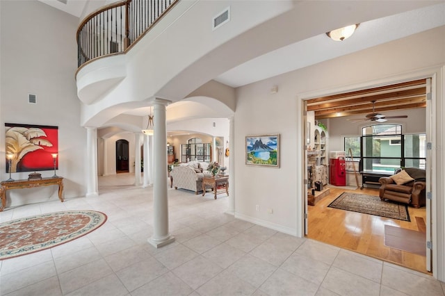 entryway with beam ceiling, light wood-type flooring, ornate columns, and ceiling fan