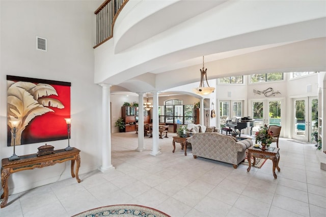 living room with light tile patterned floors, ornate columns, a high ceiling, and french doors