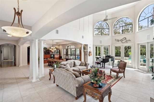 tiled living room featuring french doors, a high ceiling, and ceiling fan with notable chandelier