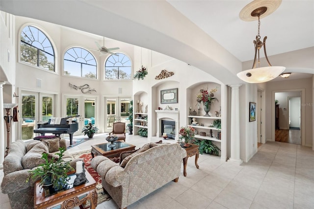 tiled living room with french doors, decorative columns, built in features, and ceiling fan