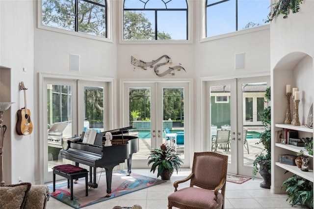 living area with french doors, a towering ceiling, and light tile patterned floors