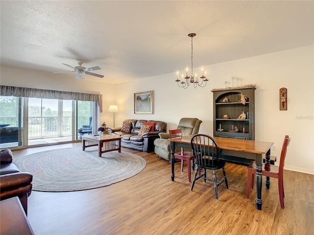 living room with a textured ceiling, ceiling fan with notable chandelier, and light hardwood / wood-style flooring