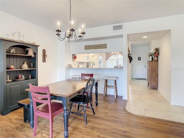 dining space with light tile floors, a chandelier, and sink