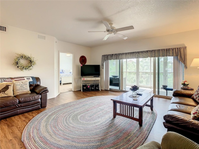 living room with a textured ceiling, light hardwood / wood-style floors, and ceiling fan