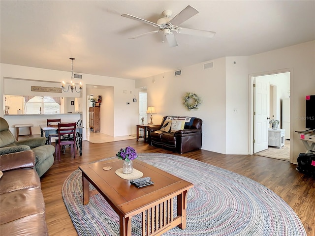 living room with ceiling fan with notable chandelier and hardwood / wood-style flooring