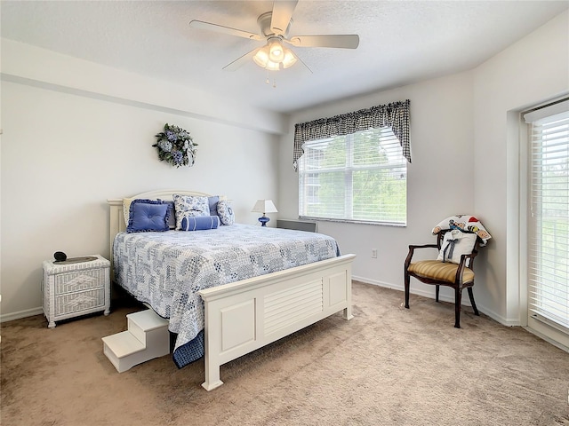 bedroom featuring light colored carpet, ceiling fan, and multiple windows